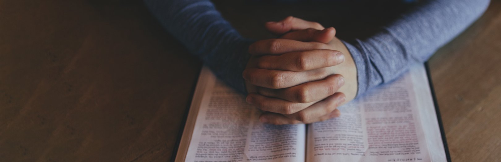 folded hands on bible