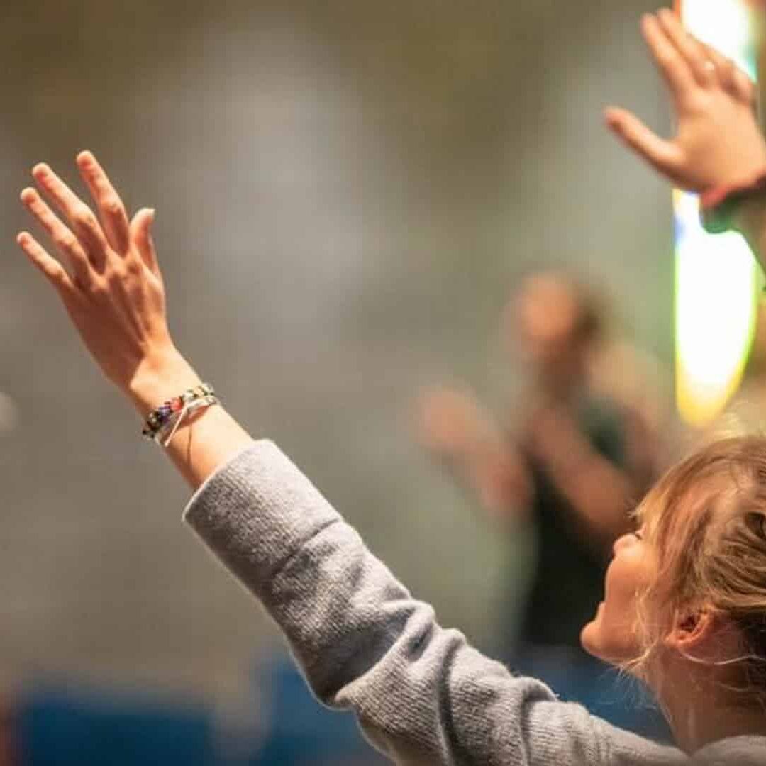 Grace Student raising her hand in a worship chapel