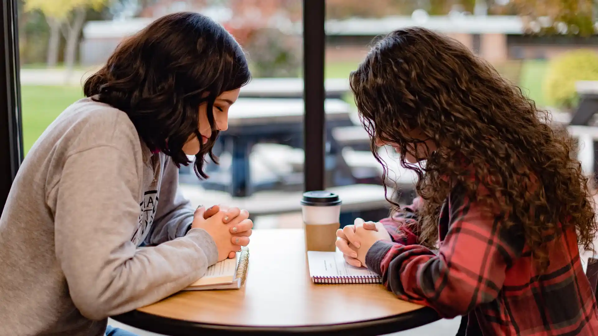 Two Psychology students praying at table in the Commons.