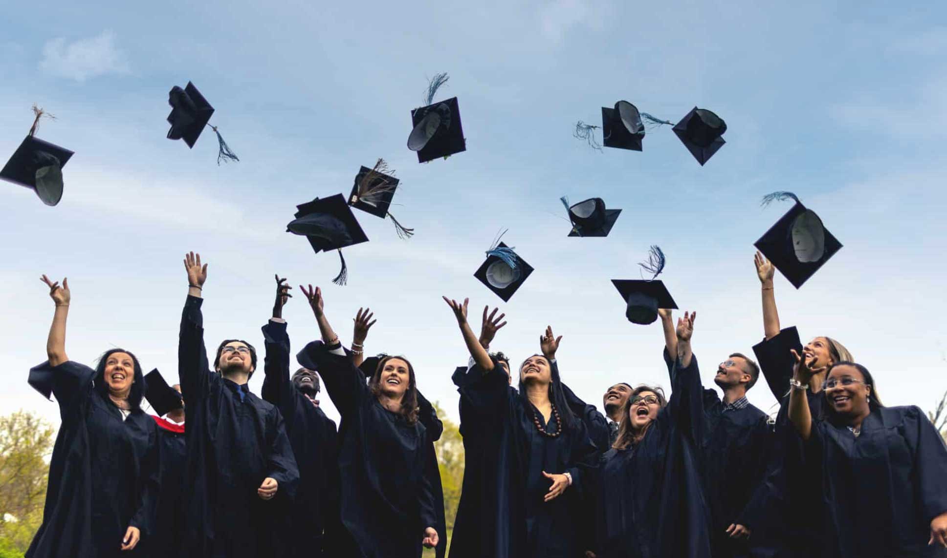 happy graduates tossing their caps in the air