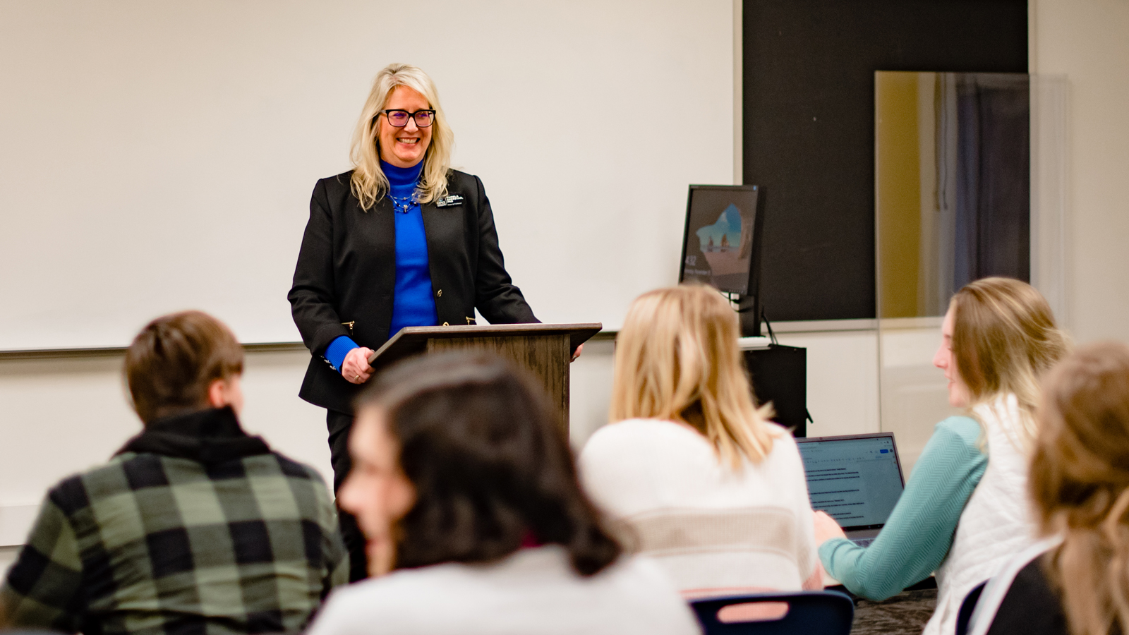 A happy professor standing in front of a classroom of students