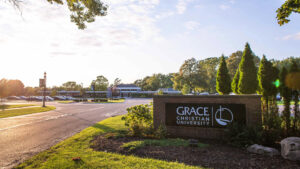 The main entrance of Grace Christian University showing the road sign and main building in the distance