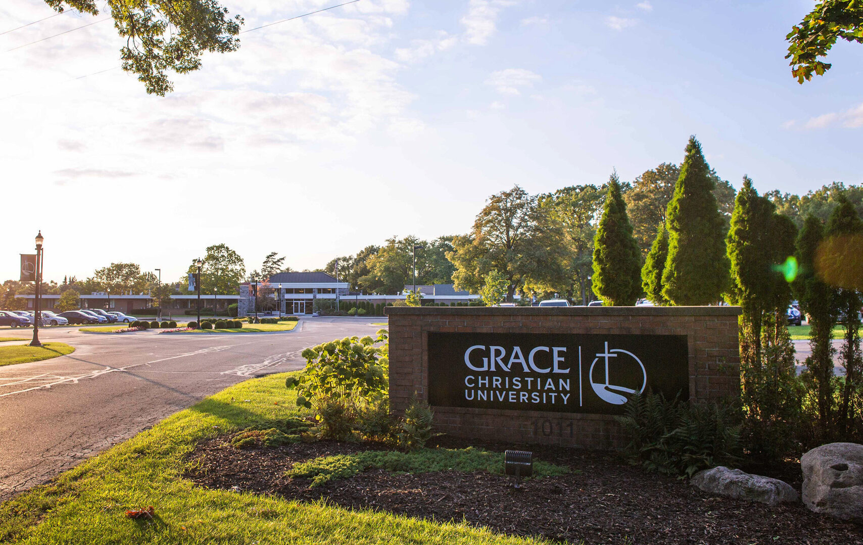 The main entrance of Grace Christian University showing the road sign and main building in the distance