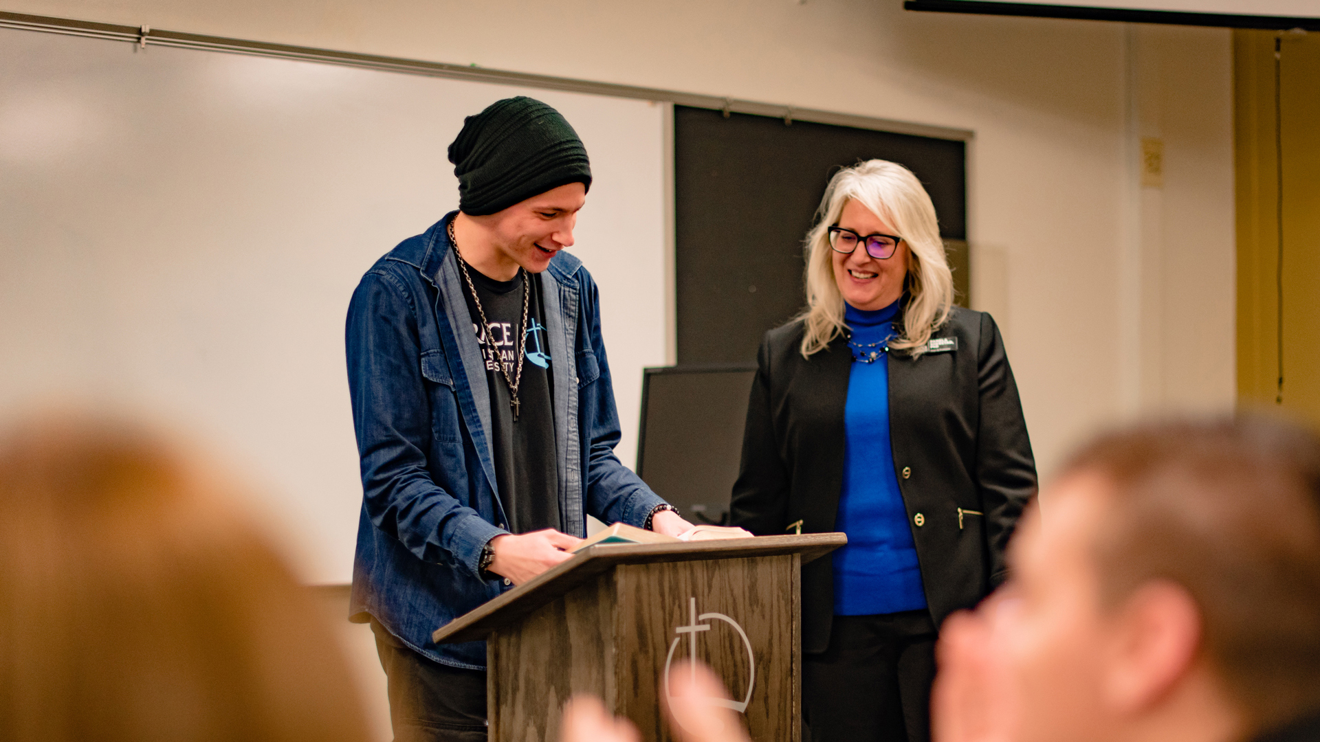A Grace student and a Professor standing together at the front of a classroom.