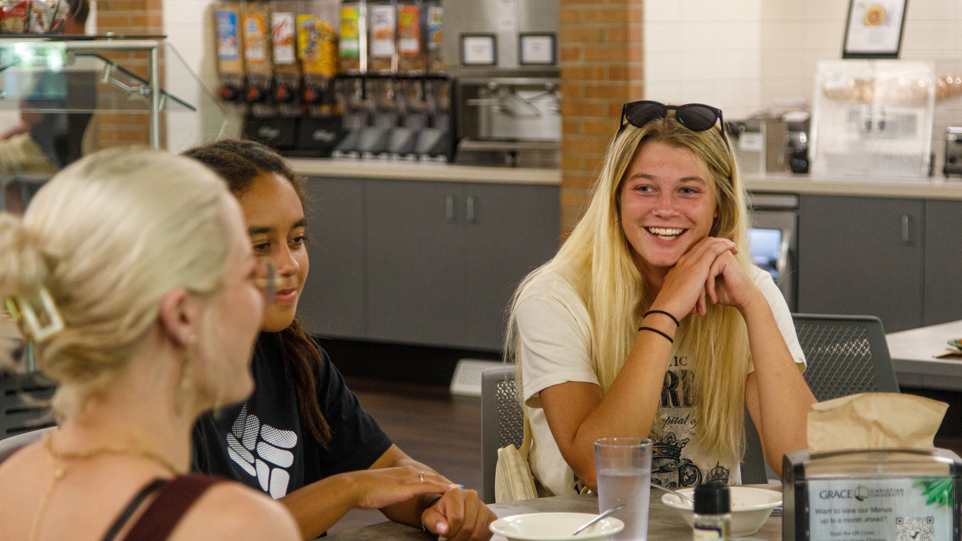 Happy Grace Students sit around a table in the dining hall, at Grace Christian University, during a Campus Tour