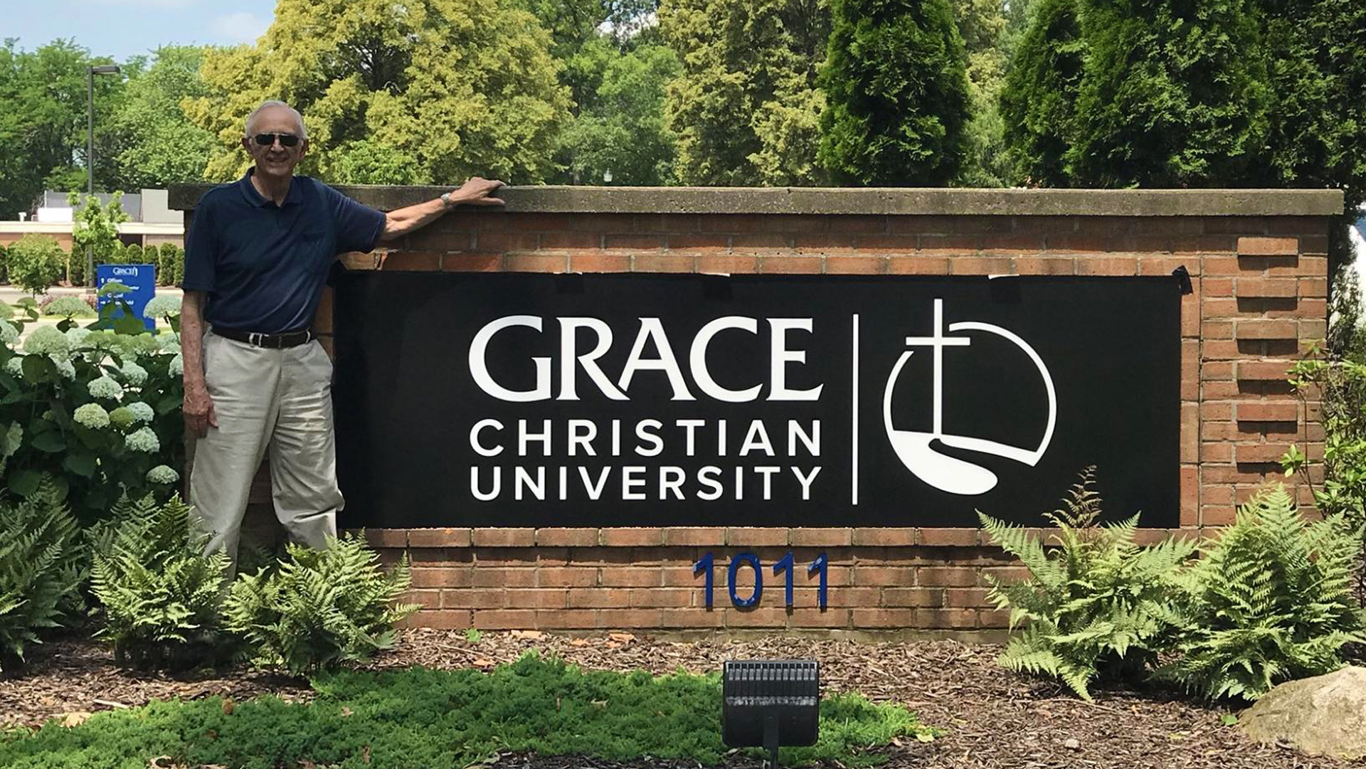 Sam Vinton standing by the Grace Christian University sign at the front entrance.