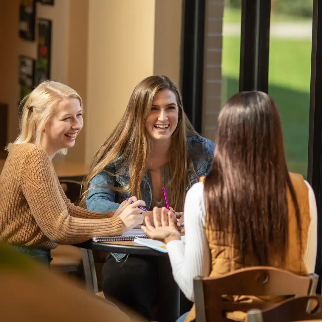 A group of Grace Students studying around a table in the Commons