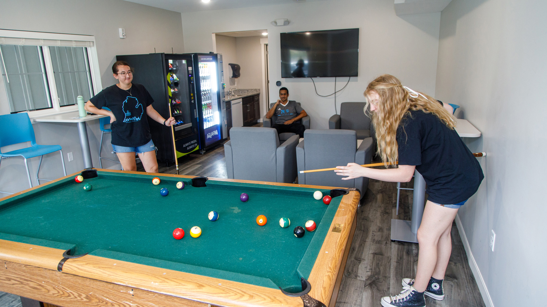 Grace students relaxing on chairs and playing pool in the Hilltop Community Room.