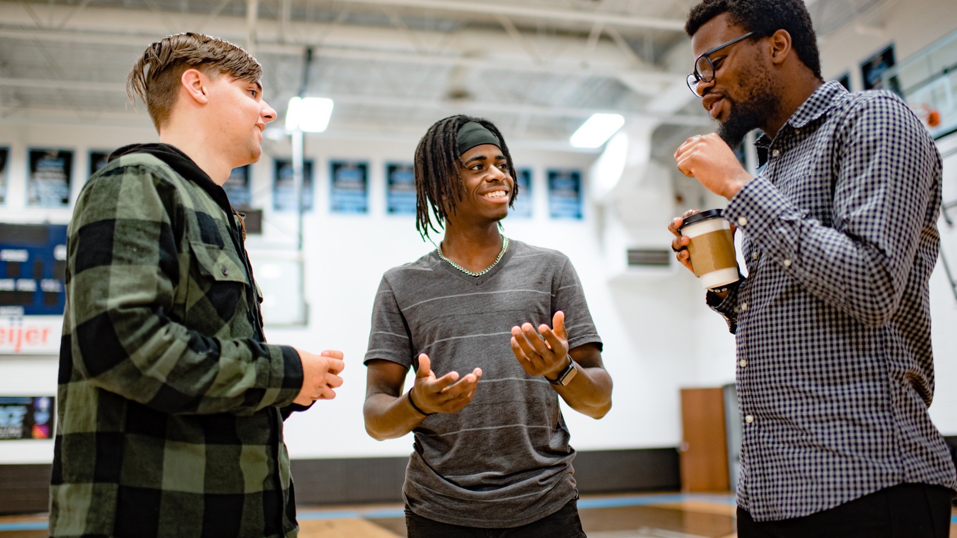 Three male Grace students having a conversation in the Aldrich Athletic Center Gym.