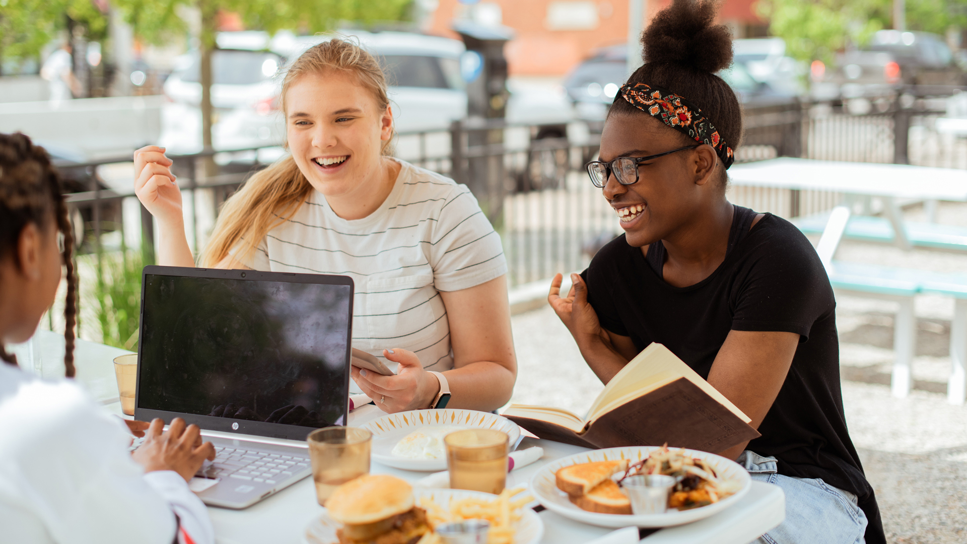 Happy Grace Students sitting around a table outdoors with a laptop and books.