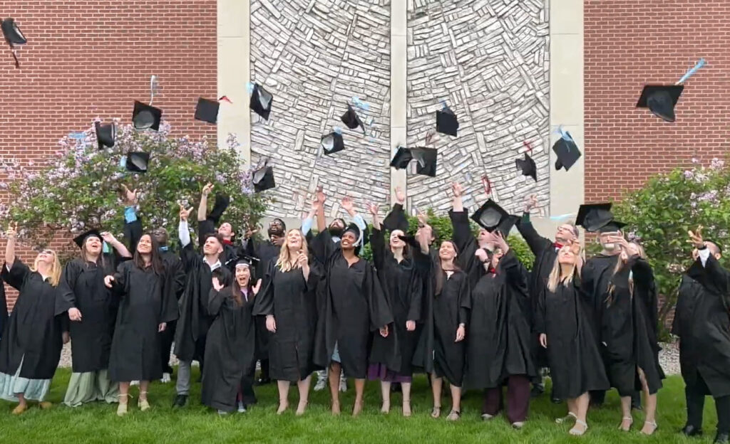 A group of Grace Graduates tossing their hats in the air.