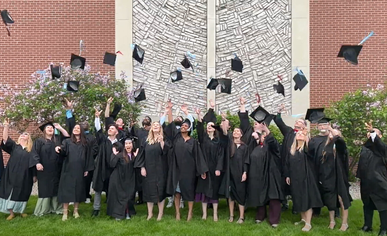 A group of Grace Graduates tossing their hats in the air.