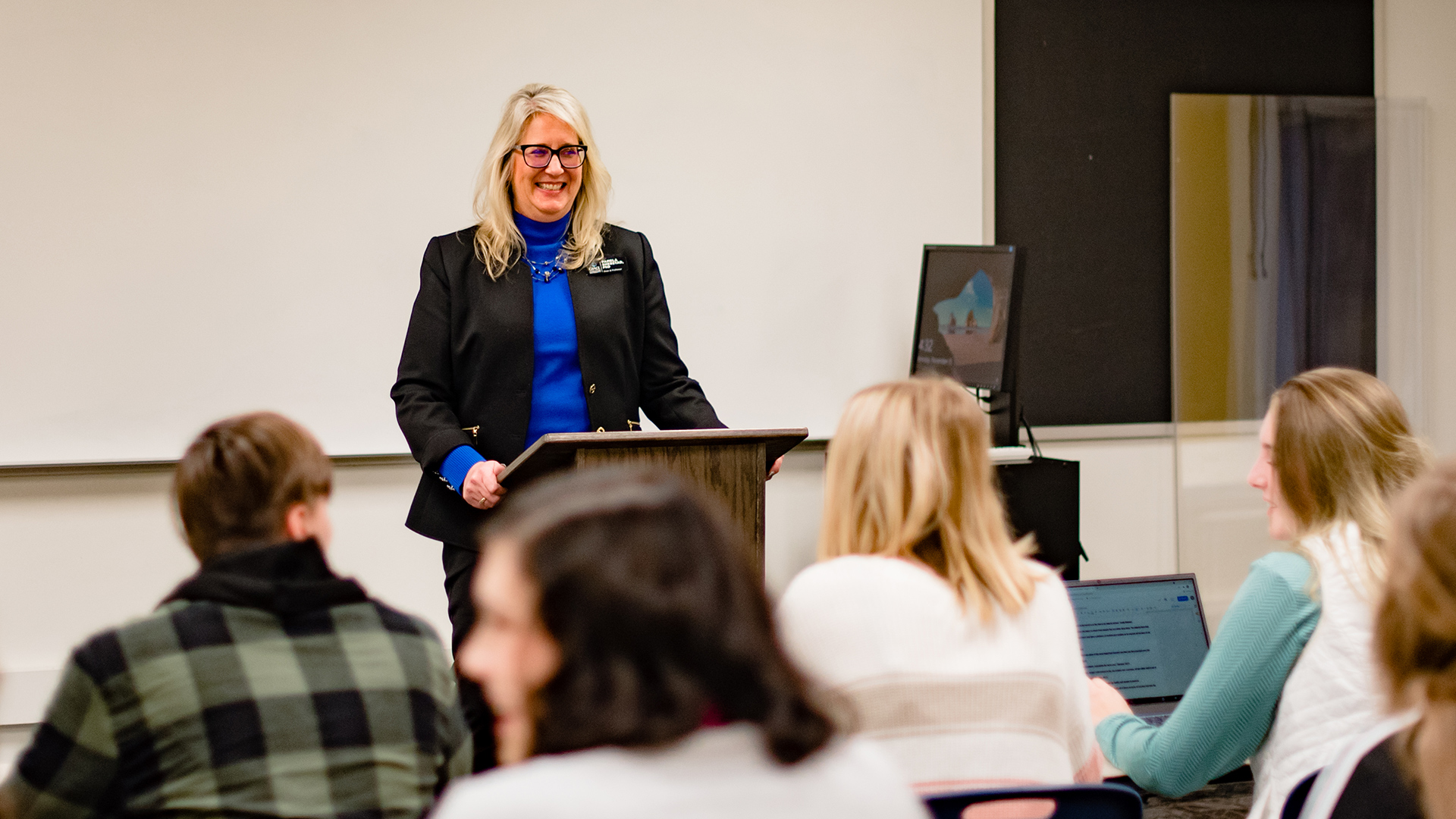 Happy Communications Professor teaching a classroom of students.