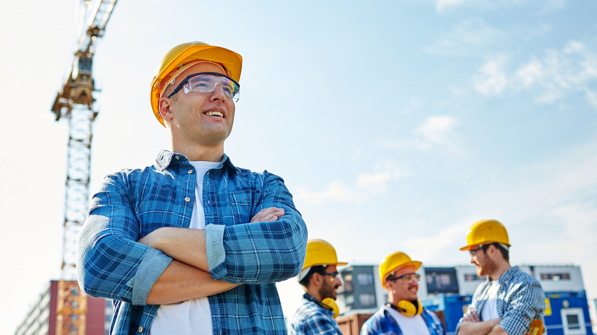 A group of builders on a construction site, with a crane in the background